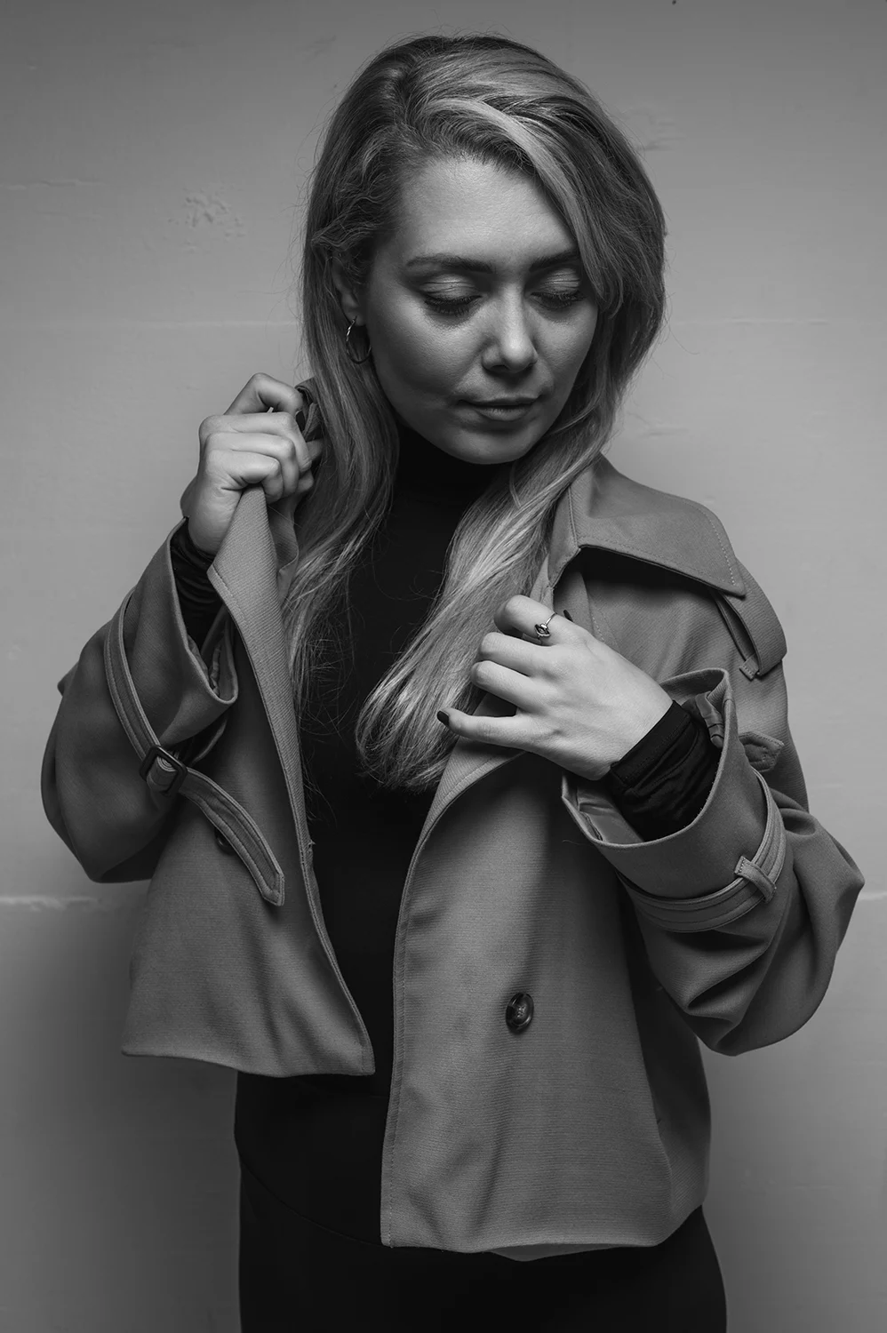 Blonde Frau mit Trenchcoat schaut nach unten
